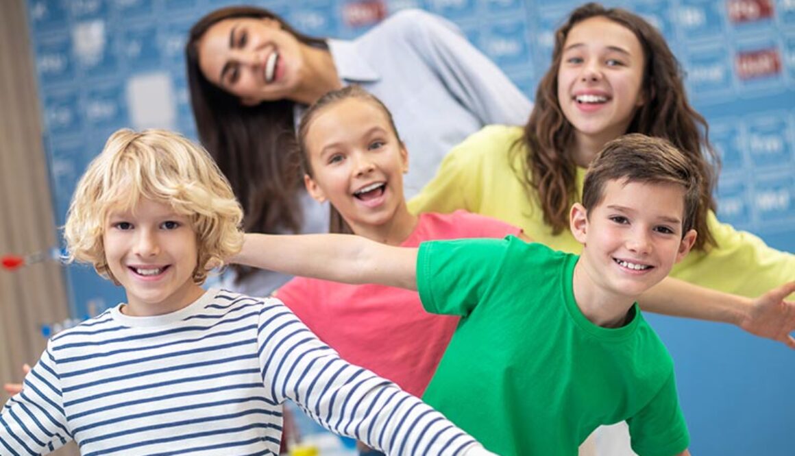Students smiling with their teacher in class