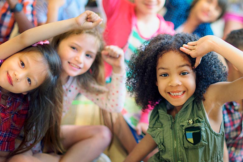 Elementary school kids smiling at the camera and seated in their class