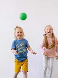 Elementary school kids playing with colorful balls and laughing with each other